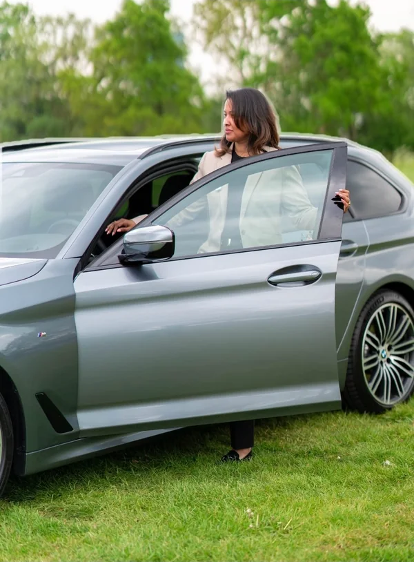 Female executive chauffeur next to a BMW 5 Series Touring